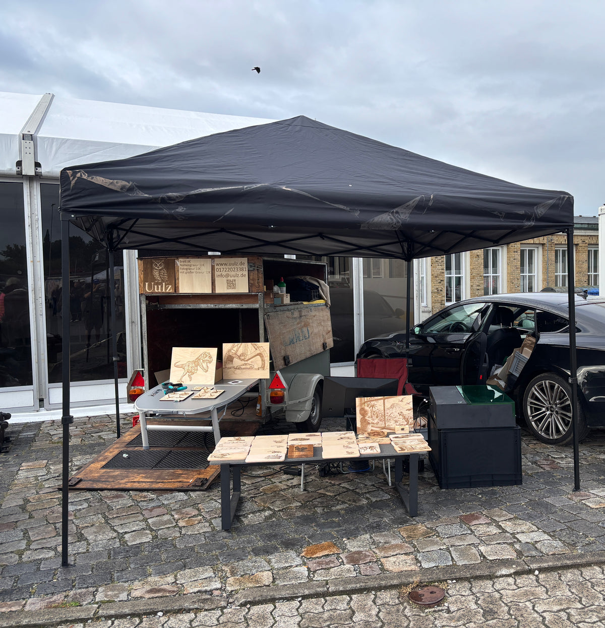 Flohmarktstand von Uulz: Pavillon mit gravierten Holzbrettern und Holzbildern auf Tischen